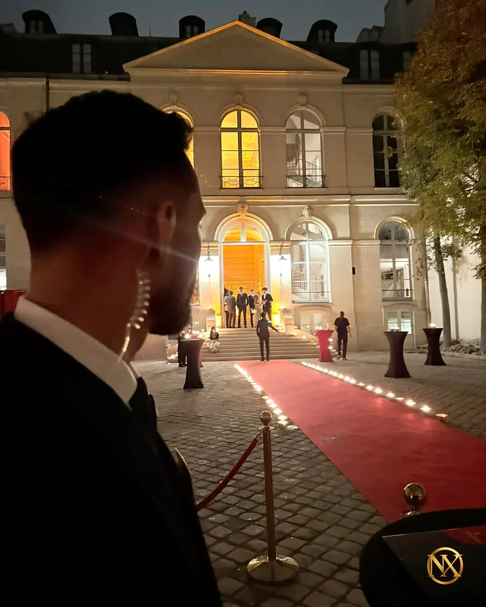 Agent NOX SECURITY en costume, avec oreillette, surveillant l’accès à la réception par le tapis rouge