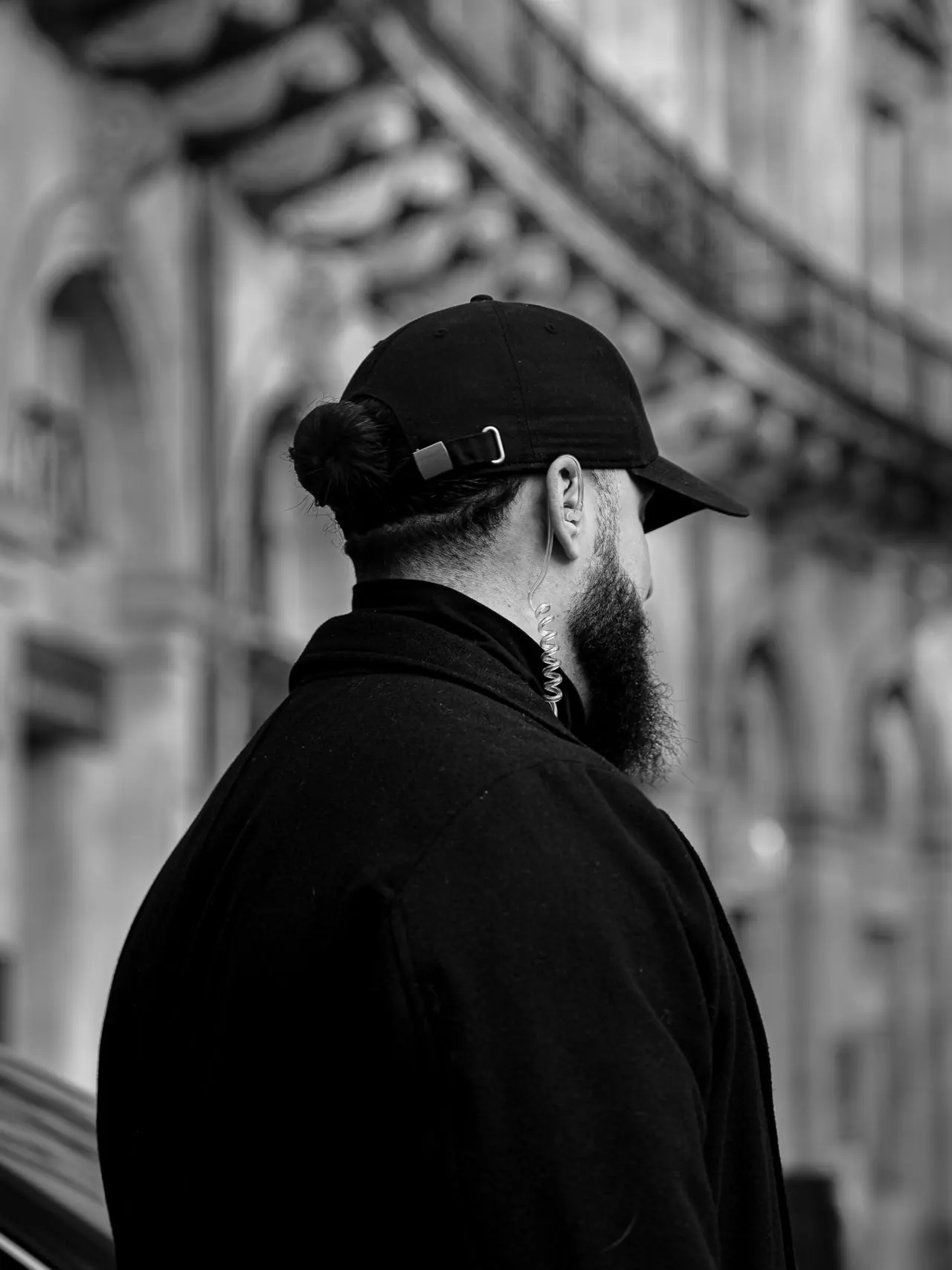 Agent Nox Protec de dos, oreillette, devant une façade bordelaise
