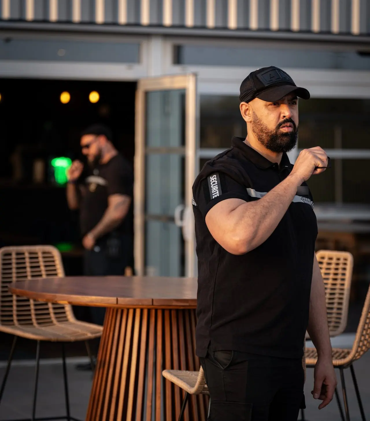 Agent NOX SECURITY en liaison radio devant une terrasse